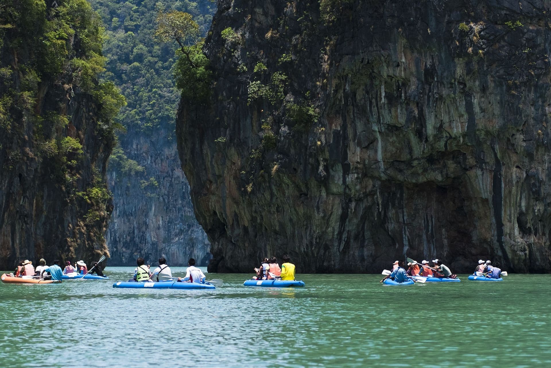 Tourists kayaking through limestone cliffs in Phang-nga Bay of Thailand