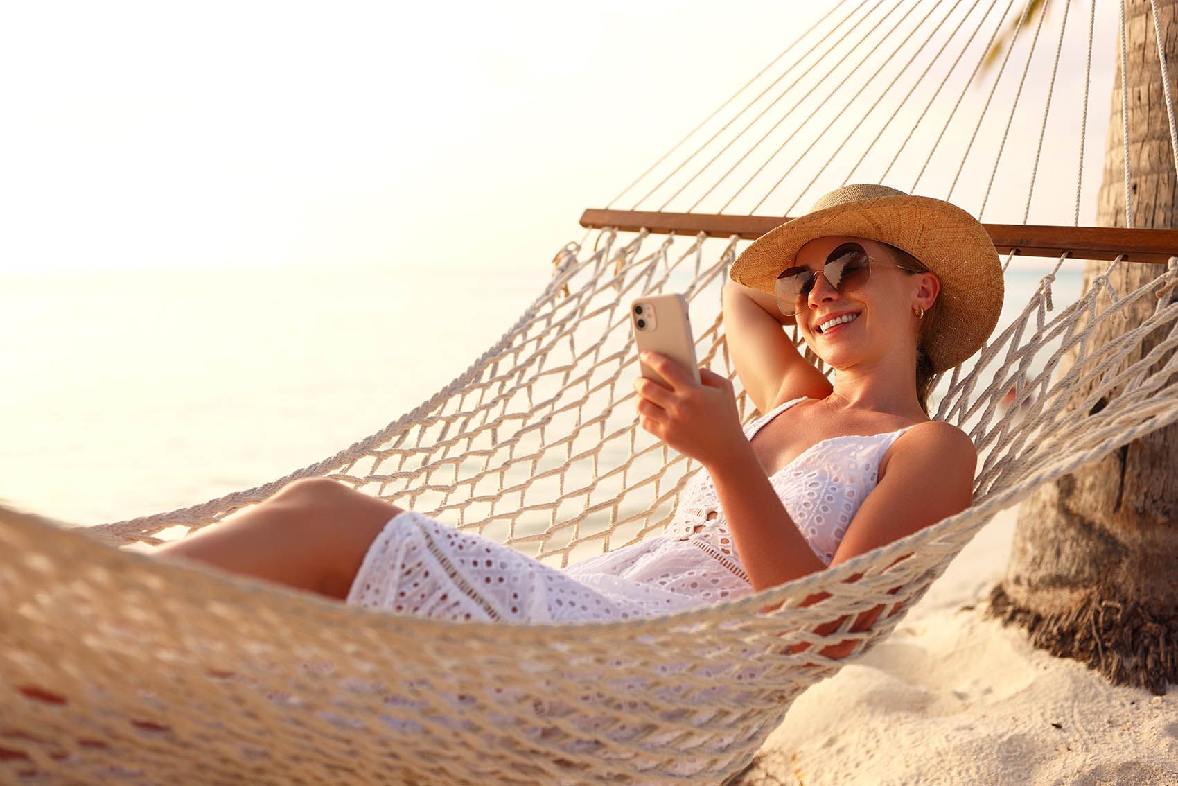 Young happy woman, female freelancer in straw hat and sunglasses working on smartphone  © Shutterstock